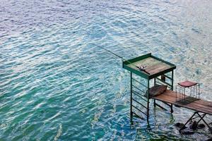 A fishing rod rests on a high wooden platform near the river bank. photo
