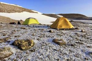 Tents of tourists are located at the foot of a snow-covered mountain. photo