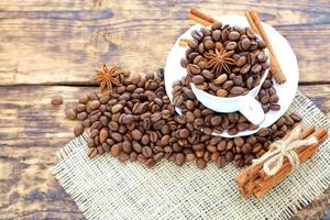 Grain coffee in a cup on a wooden background. Cinnamon on a napkin and tied with string. Anise stars complement the aroma of coffee. photo