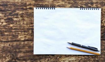 Empty notebook with a pencil and black pen on an old textural wooden surface. photo