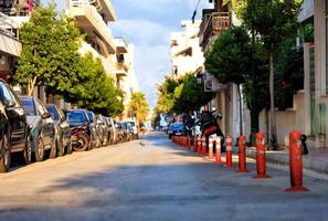 la parte peatonal de la carretera está dividida por columnas rojas en una calle de la ciudad a la luz del sol. foto