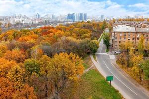 Bright orange foliage of the city park in the autumn landscape of the city, view from the top.