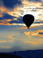 silueta de una pareja amorosa y un globo contra el cielo de la mañana con nubes rojas ardientes foto