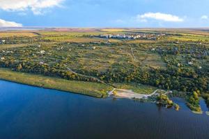 Aerial photography, the river bank against the background of sunset summer sunbeams, steppe trees and a working village in the background. photo