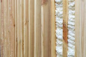 un ejemplo de cómo llenar el espacio entre los tablones de madera verticales con espuma de construcción. foto