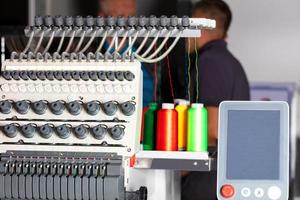 Industrial embroidery machine with multicolored threads, close-up. photo