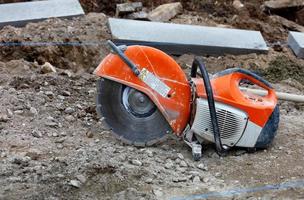 Petrol saw with diamond wheel on construction site gravel in front of concrete parapets. photo