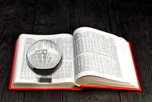 Crystal ball and book of ephemeris on blurred old black wooden background. photo