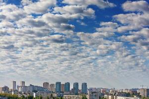 Small white-gray clouds gradually obscure the blue sky above the city. photo