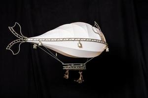 Steampunk airship toy soars on a black background. Souvenir and handicraft, copy space. photo
