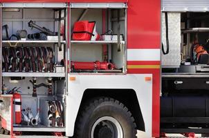 mangueras contra incendios, válvulas y grúas, conos de transporte, extintores manuales se encuentran en el compartimiento de carga de un camión de bomberos equipado.