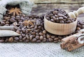 Grain coffee in a wooden cup and burlap. Cinnamon sticks are tied with string. Anise and dried slices of lemon on an old wooden board. photo