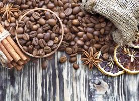 Grain coffee in a wooden cup and burlap. Cinnamon sticks are tied with string. Anise and dried slices of lemon on an old wooden board. photo