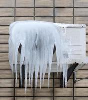 large heavy ice jets hang on the external unit of the air conditioner photo