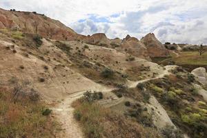 A winding mountain trail passes between huge and old stones in the Cappadocian red valley. photo