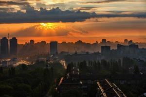 Los rayos del sol atraviesan las nubes de lluvia de una nube al amanecer e iluminan una ciudad dormida. foto