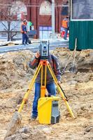 un ingeniero de servicio vial utiliza un nivel láser en un sitio de construcción. foto