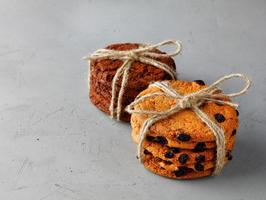 Stacks of homemade oatmeal and chocolate chip cookies tied with string on a gray concrete surface. Copy space. photo
