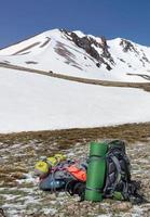 Camping equipment against the background of a snow-capped mountain and blue sky. photo