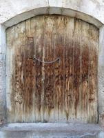 Ancient trapezoidal antique wooden doors with a metal lock in the middle photo
