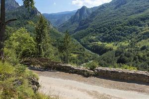 Part of the stone road running serpentine among the mountains and a clear turquoise mountain river flowing into the gorge. Ecological concept, pure nature. photo