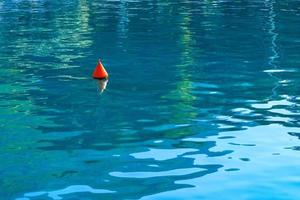 An orange buoy sways on the turquoise sea waves of the Gulf of Corinth. photo