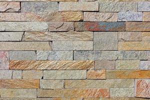 The texture of the old wall lined with shiny rough sandstone tiles. photo