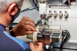The foreman adjusts the correct operation of a modern sewing machine. photo
