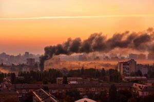 Paisaje urbano temprano en la mañana con humo negro de la conflagración. foto