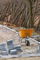 Old yellow construction wheelbarrow against the background of a stack of paving slabs. Vertical image. photo