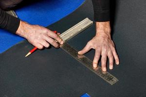 A worker marks out a sheet of roofing iron with a pencil and a ruler. photo