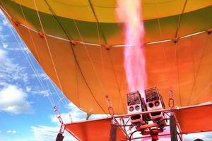 Fire of coral color comes out of a powerful gas torch and fills balloon balloon with hot air.
