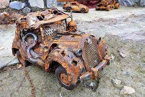 Rusty toy car with a chain made of household waste. photo