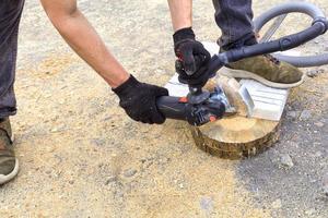 The worker cuts a metal plate and paving slabs for laying on the terrace with an angle grinder. photo