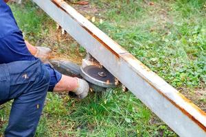The worker cuts the metal channel with an angle grinder and an abrasive reinforced disc for metal. photo