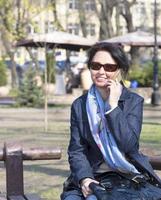 Una mujer joven con un estado de ánimo alegre se comunica en un teléfono inteligente en un parque de primavera