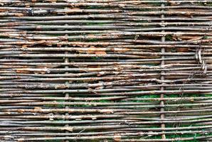 Fragment of a wicker fence made of old branches close-up in bright sunlight. photo