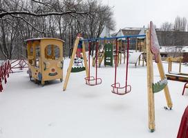 Swing on the playground was covered with snow photo