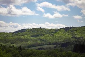 Scenic green rolling hills against the blue sky with clouds. photo