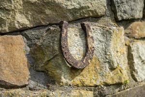 Close-up of an old rusty horseshoe propped on a big stone.