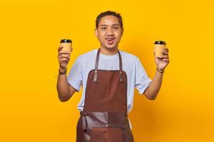 retrato, de, alegre, barista, hombre, tenencia, dos, papel, tazas de café, para elegir, aislado, en, fondo amarillo foto
