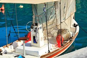 View of the captains bridge and steering wheel of a small wooden fishing schooner with hanging fishing tackle. photo