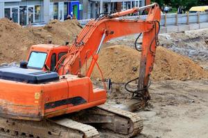Heavy construction excavator crawler bucket digs a trench during a collector repair on a city street. photo