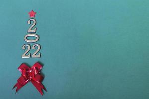 Holiday concept. Christmas background, golden numbers 2022 with red bow and star. Happy New Year. Vertical photo