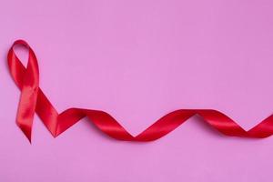 Top view on pink background with red ribbon concept December 1st International AIDS Day close-up. photo