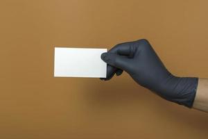 White business card mockup on colored background. A hand in a medical glove holds a business card photo