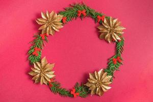 Christmas wreath of fir branches and decorations on a red background. Flat lay, top view, copy space. festive composition photo