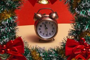Close up. Christmas wreath with decorations and alarm clock on a colored background. Copy photo