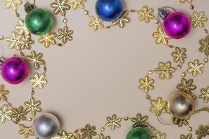 Fondo beige navideño con abeto brillante, juguetes coloridos y decoración dorada. foto