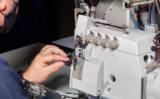 The foreman adjusts the work of a modern electric sewing machine and overlock. photo